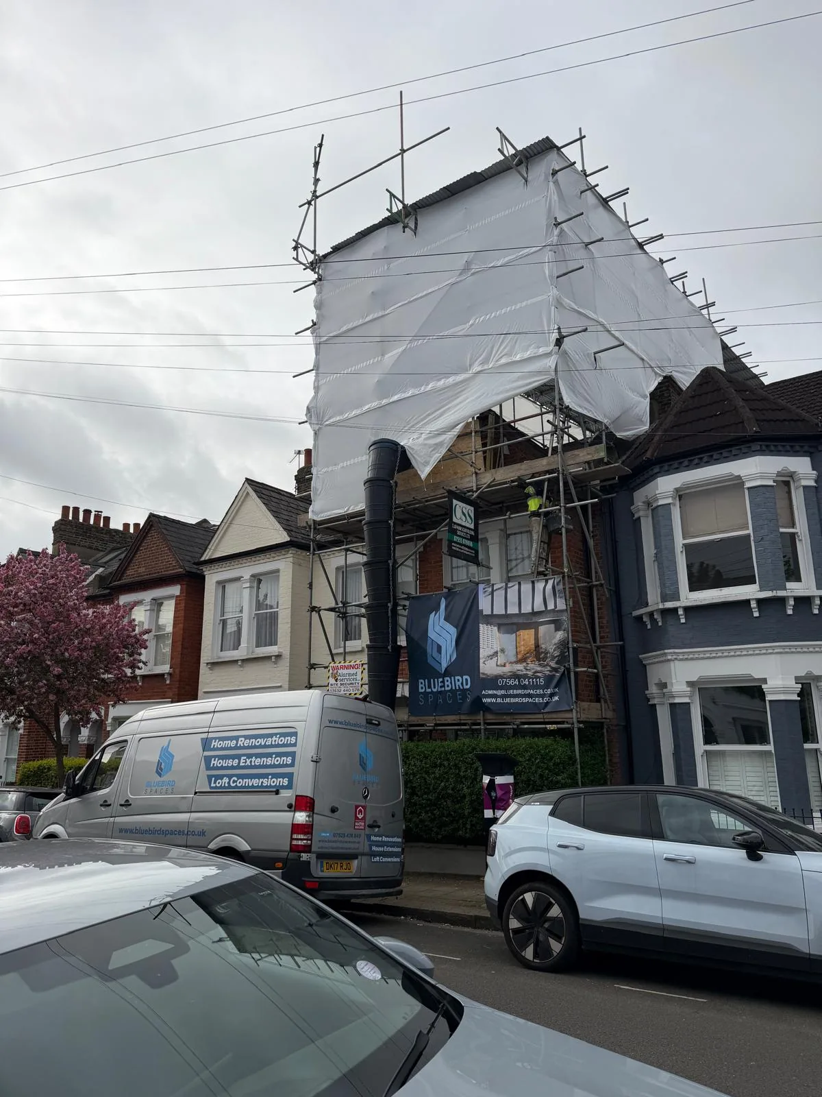 Scaffolded Bluebird Spaces loft conversion site with branded van in South West London